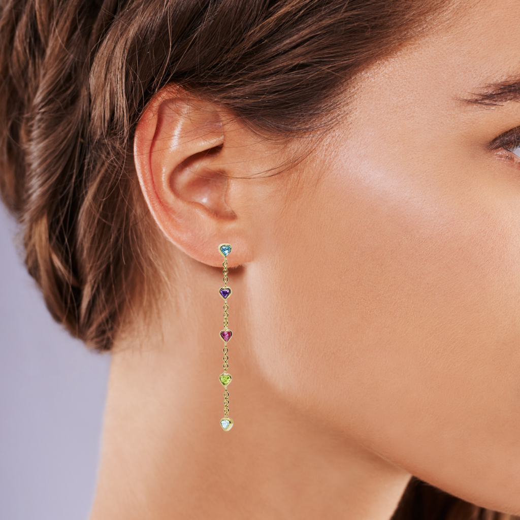 Close-up of a woman wearing colorful drop earrings with a neutral background