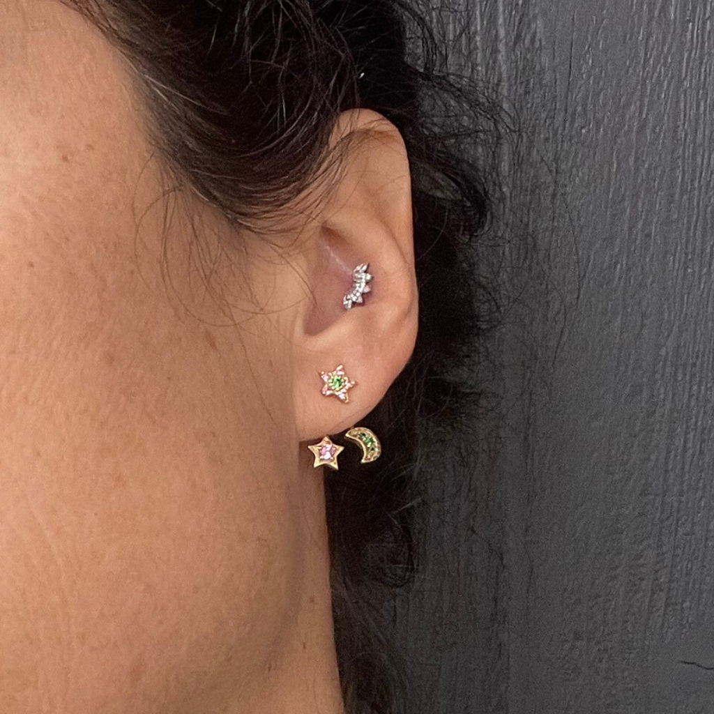 Close-up of an ear with multiple earrings against a dark background